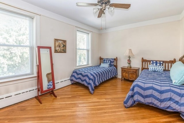 bedroom with baseboard heating, ceiling fan, and light hardwood / wood-style flooring