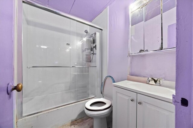 full bathroom featuring shower / bath combination with glass door, vanity, toilet, and hardwood / wood-style flooring