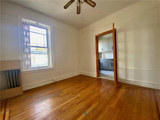 spare room featuring sink, light wood-type flooring, and ceiling fan