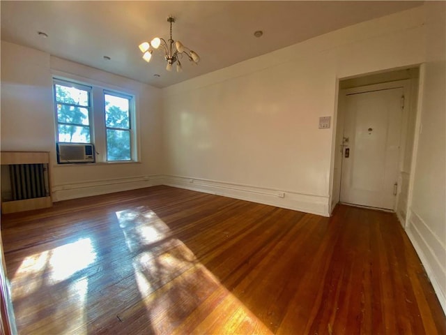 spare room featuring a baseboard radiator, dark wood-type flooring, cooling unit, and a notable chandelier