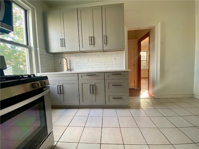 kitchen featuring backsplash, sink, light tile patterned flooring, gray cabinets, and appliances with stainless steel finishes