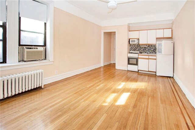 kitchen featuring white appliances, white cabinetry, light wood-type flooring, and radiator