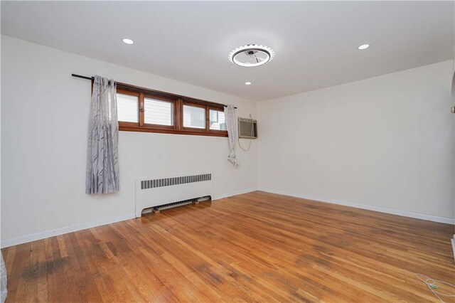 empty room featuring radiator, wood-type flooring, and an AC wall unit