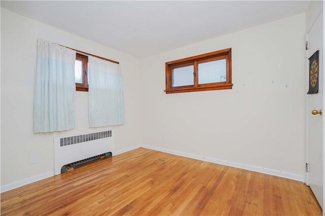 empty room featuring radiator heating unit and hardwood / wood-style flooring