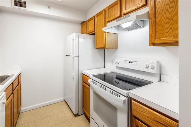 kitchen with light floors, light countertops, brown cabinetry, white appliances, and under cabinet range hood