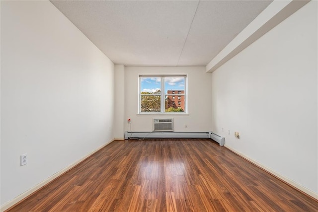 spare room with dark hardwood / wood-style flooring, a baseboard heating unit, and an AC wall unit