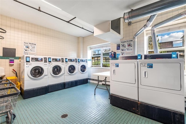 laundry room with tile patterned flooring, tile walls, and independent washer and dryer