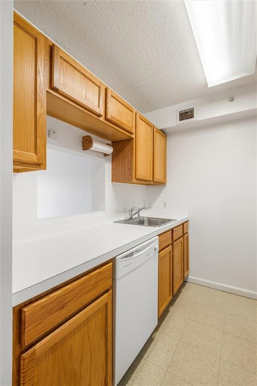 kitchen featuring visible vents, white dishwasher, light countertops, light floors, and a sink