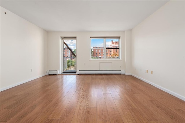 unfurnished room featuring a baseboard radiator and light hardwood / wood-style floors