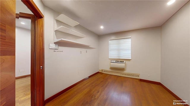 empty room with baseboard heating, baseboards, wood finished floors, and recessed lighting