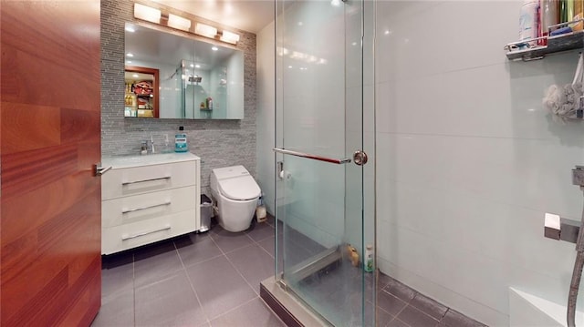 bathroom featuring tile patterned floors, toilet, vanity, tile walls, and a stall shower