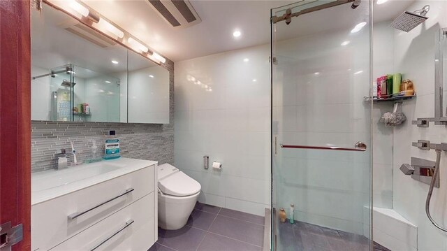 bathroom featuring walk in shower, tile patterned floors, toilet, vanity, and tile walls