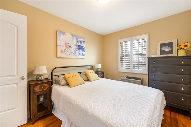 bedroom featuring dark hardwood / wood-style flooring and a wall mounted AC