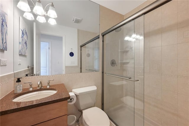 bathroom with vanity, a shower with shower door, tile walls, and toilet