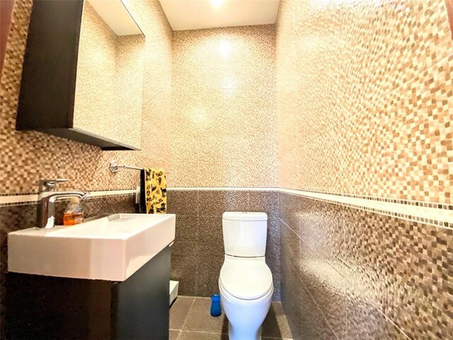 bathroom featuring vanity, toilet, tile patterned flooring, and tile walls