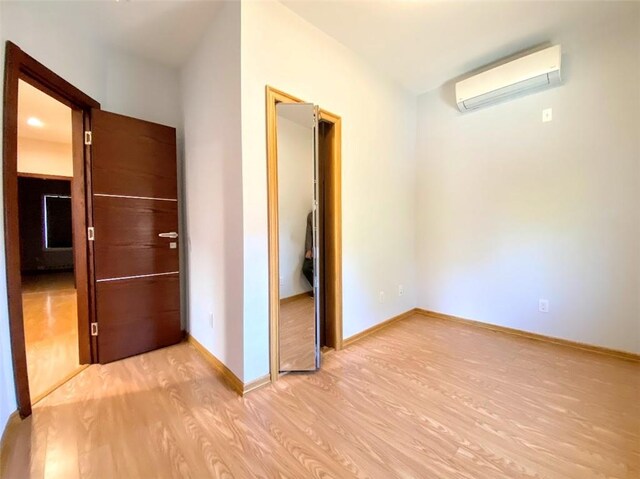 hall with a wall unit AC and light hardwood / wood-style flooring