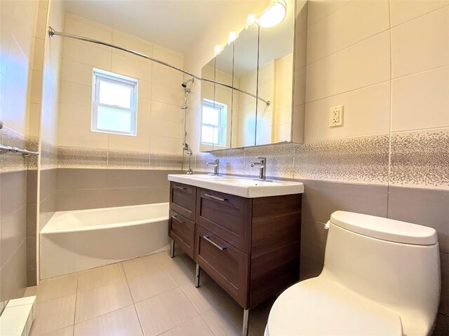 full bathroom with tile walls, vanity, tiled shower / bath, tile patterned floors, and toilet