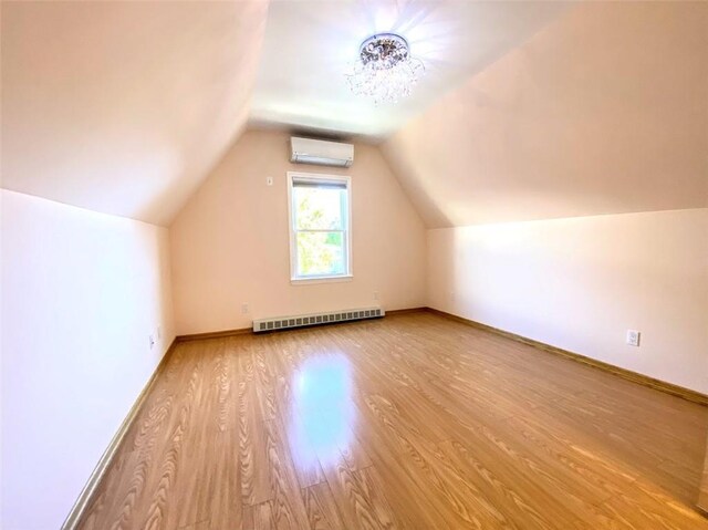 bonus room featuring lofted ceiling, a wall unit AC, and light hardwood / wood-style floors