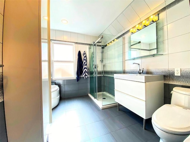 bathroom featuring a shower with door, tile walls, tile patterned flooring, vanity, and toilet