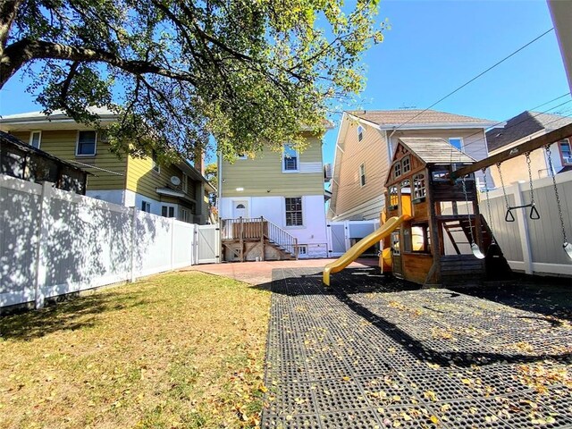 rear view of house featuring a playground and a lawn