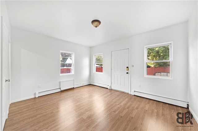 entryway with a healthy amount of sunlight, baseboard heating, and light hardwood / wood-style flooring