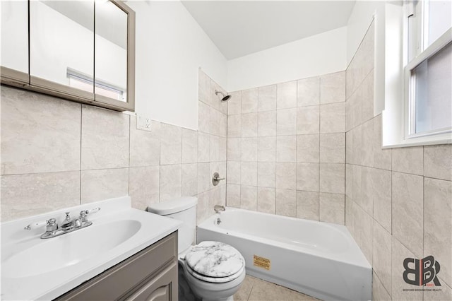 full bathroom featuring tile walls, tiled shower / bath combo, vanity, and toilet