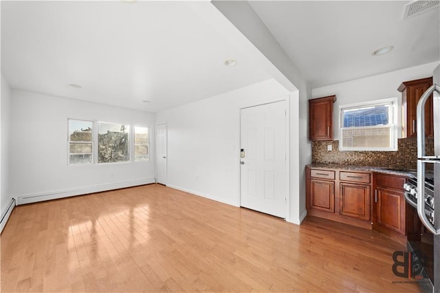 interior space featuring a baseboard heating unit, tasteful backsplash, light wood-type flooring, and dark stone counters