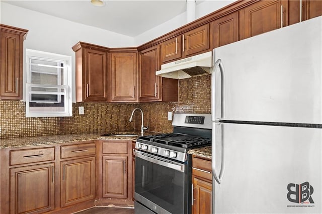 kitchen with gas stove, white refrigerator, sink, backsplash, and light stone counters