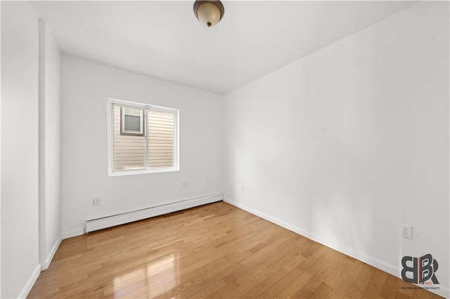 empty room featuring a baseboard heating unit and light hardwood / wood-style flooring