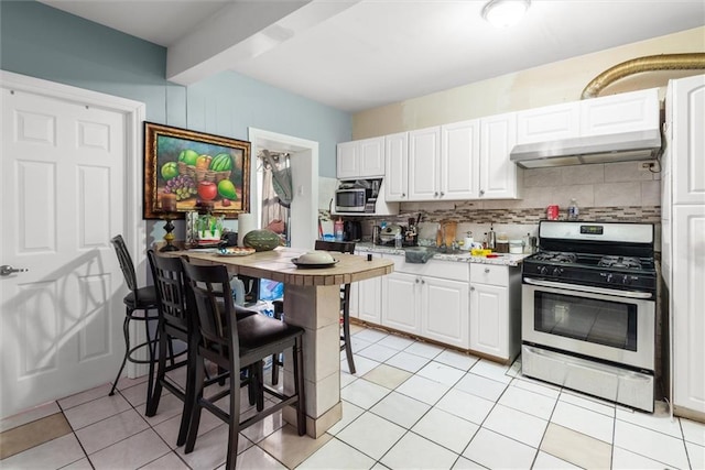 kitchen featuring white cabinetry, stainless steel appliances, light tile patterned flooring, and backsplash