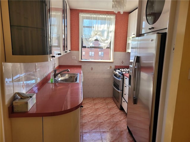 kitchen featuring a sink, stainless steel appliances, tile walls, and light tile patterned floors