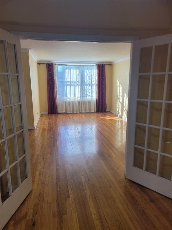 unfurnished room with baseboards, wood finished floors, and ornamental molding