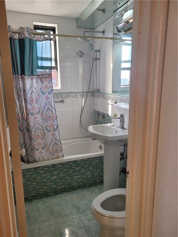 bathroom with tiled shower / bath combo, toilet, and tile patterned floors