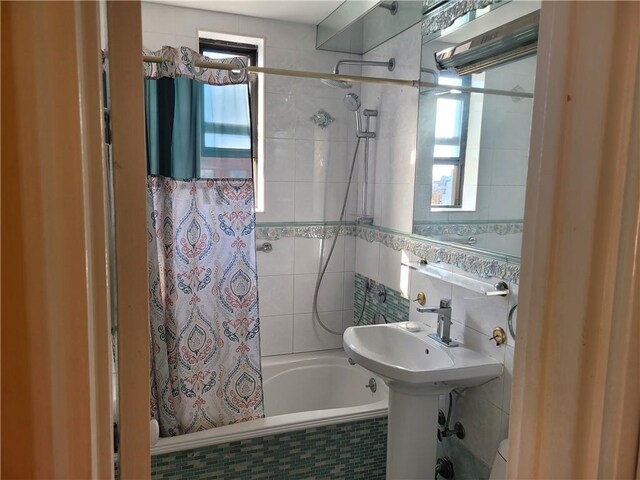 full bathroom featuring a sink, tile walls, and tiled shower / bath combo