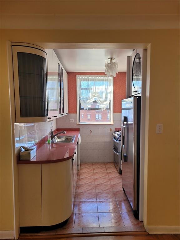 kitchen featuring dark countertops, light tile patterned flooring, appliances with stainless steel finishes, and a sink