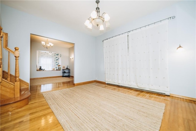 interior space featuring stairway, wood finished floors, baseboards, and a chandelier