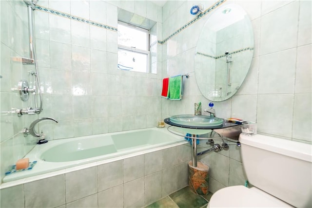 full bath featuring tiled shower / bath combo, toilet, and tile walls