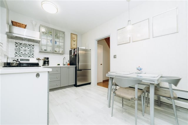 kitchen with gray cabinetry, glass insert cabinets, light countertops, decorative backsplash, and appliances with stainless steel finishes