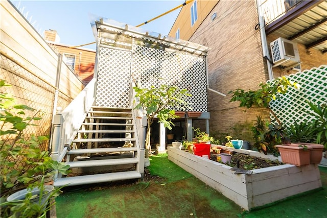 exterior space featuring a garden, brick siding, stairs, and a wall mounted AC