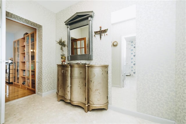 hallway featuring baseboards and wallpapered walls