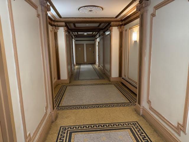 hallway with decorative columns and ornamental molding