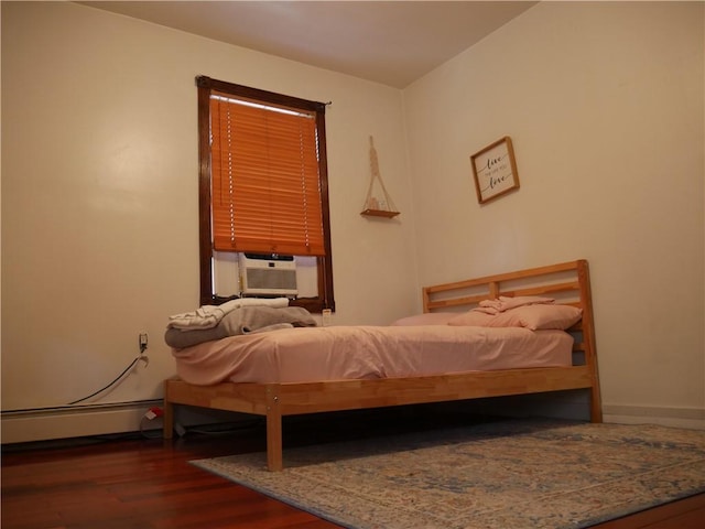 bedroom with cooling unit, a baseboard heating unit, and dark wood-type flooring