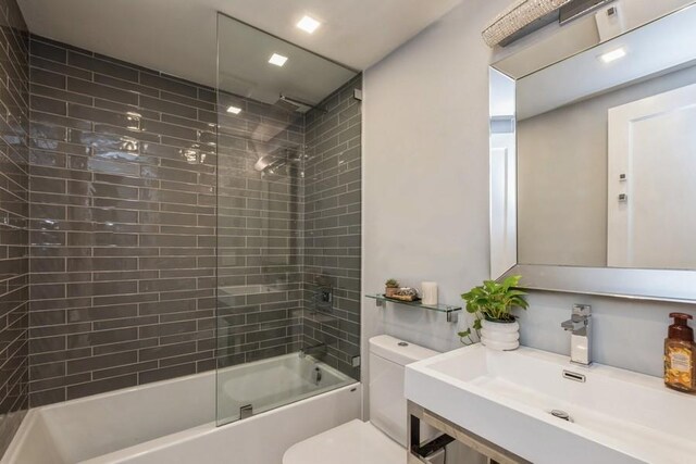 full bathroom featuring tiled shower / bath, toilet, and sink