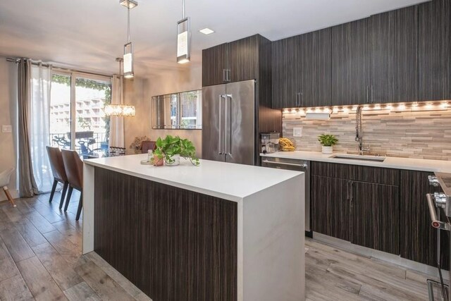 kitchen with decorative light fixtures, sink, decorative backsplash, a center island, and high end fridge