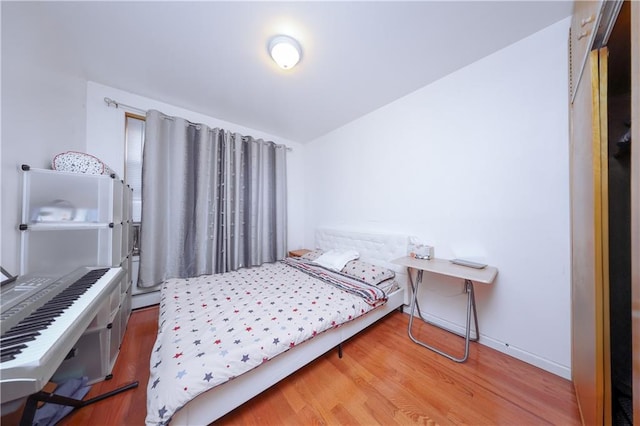 bedroom with baseboards, wood finished floors, and a baseboard radiator