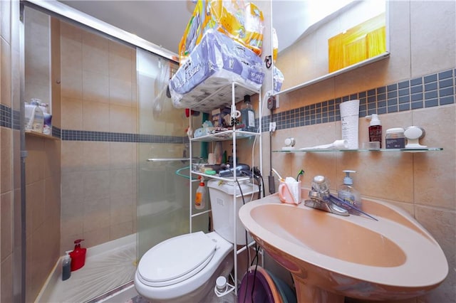 bathroom featuring a shower with door, toilet, backsplash, sink, and tile walls