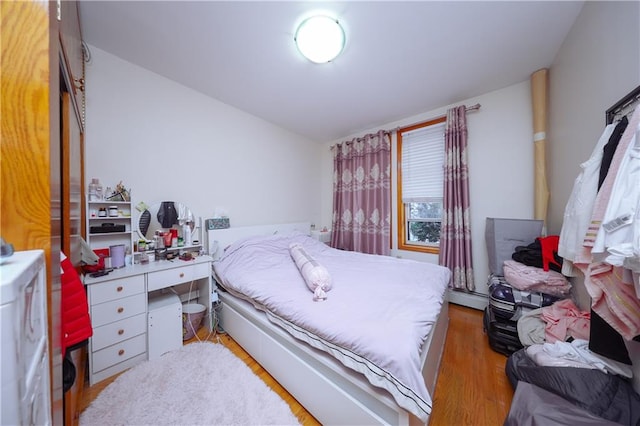 bedroom featuring baseboard heating and wood-type flooring