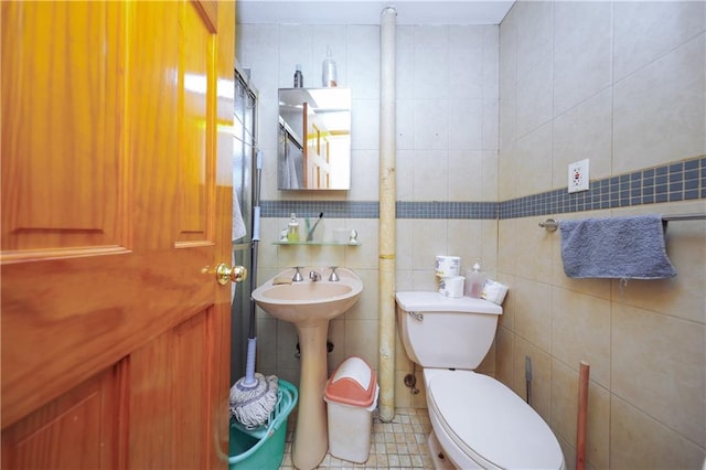 bathroom with toilet, tile walls, sink, and tile patterned flooring