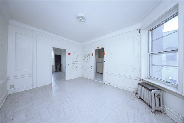 spare room with radiator heating unit and light parquet floors