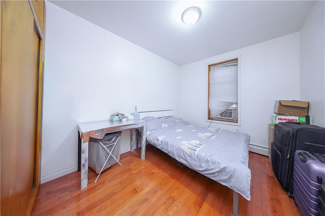bedroom featuring baseboards, baseboard heating, and light wood-style flooring